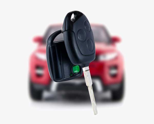 A set of car keys in front of a blurred red SUV