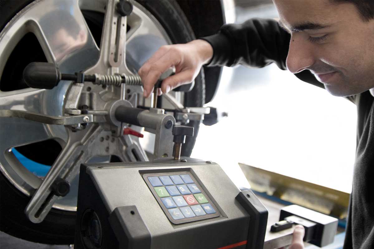 Mechanic using equipment to examine car tyre